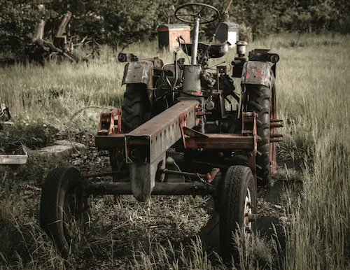 Tractor agrícola antiguo en un campo cubierto de hierba, simbolizando los inicios de la mecanización agrícola y la evolución de la Política Agraria Común en Europa.