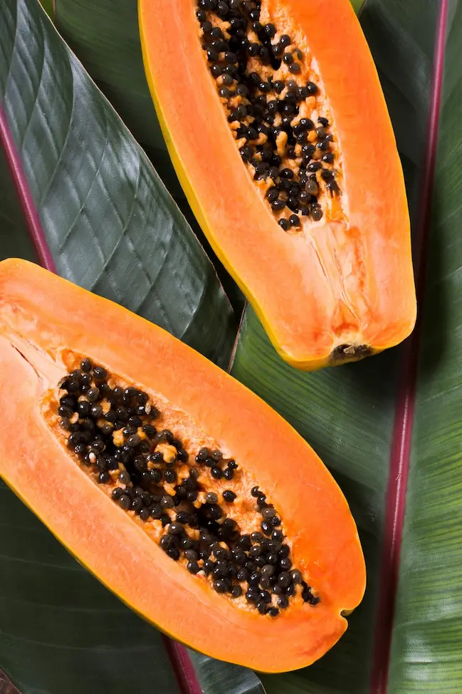 Dos mitades de papaya con pulpa naranja y semillas, mostrando la madurez y la calidad del fruto para consumo y mercado europeo.